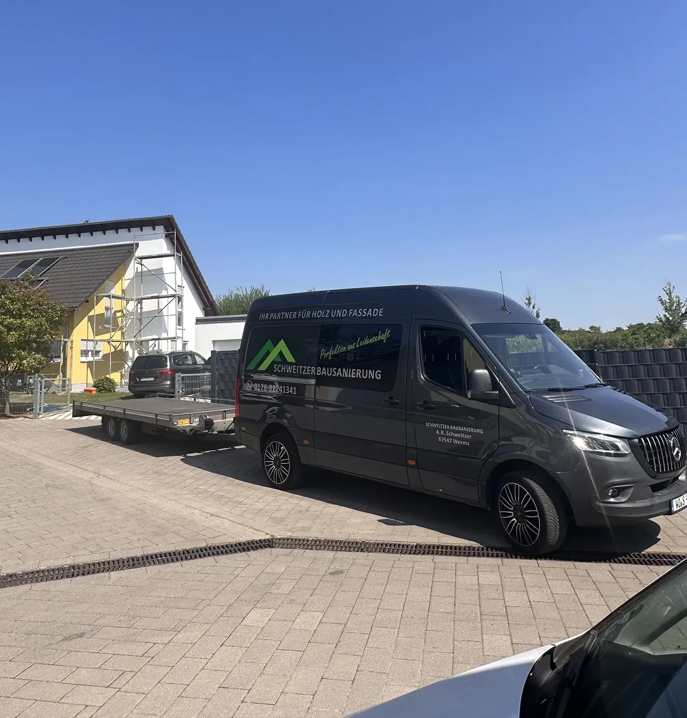 Firmenfahrzeug von Schweitzer Bausanierung mit Anhänger vor einer Baustelle